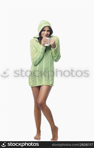 Portrait of a young woman standing and holding a cup of coffee