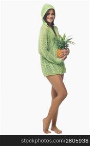 Portrait of a young woman standing and holding a pineapple