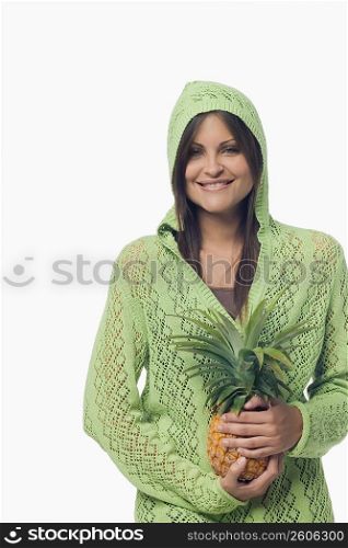Portrait of a young woman standing and holding a pineapple