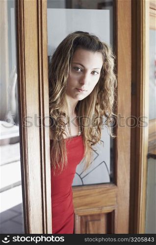 Portrait of a young woman standing at a door