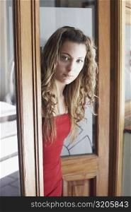 Portrait of a young woman standing at a door