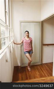 Portrait of a young woman standing at a door and smiling