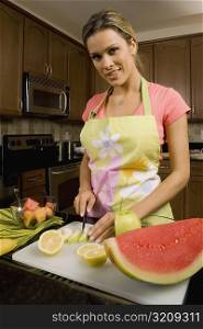 Portrait of a young woman standing at the kitchen counter cutting slices of an apple