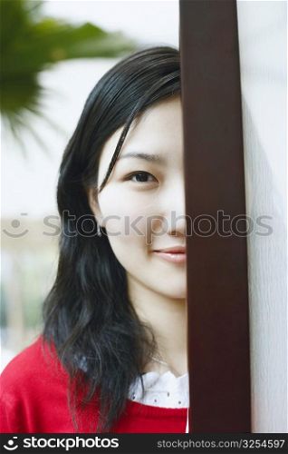 Portrait of a young woman standing behind a door