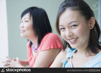 Portrait of a young woman standing in a balcony with her mother and smiling