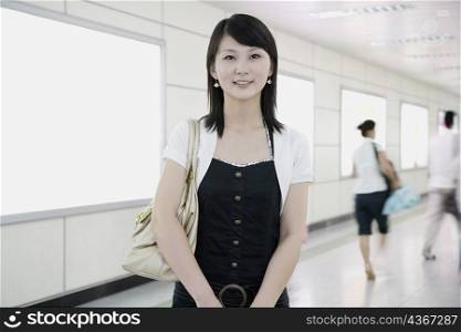 Portrait of a young woman standing in a corridor and smiling