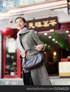 Portrait of a young woman standing in front of a store