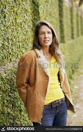 Portrait of a young woman standing in front of an ivy covered wall