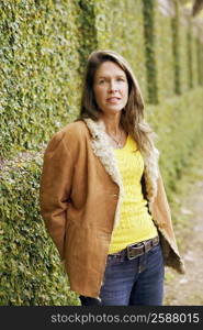 Portrait of a young woman standing in front of an ivy covered wall