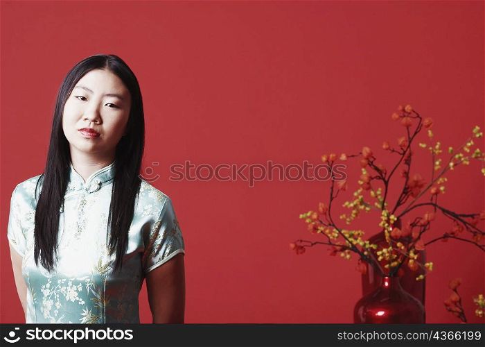 Portrait of a young woman standing near a flower pot