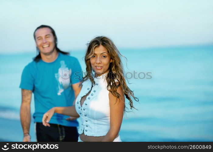 Portrait of a young woman standing on the beach with a mid adult man beside her