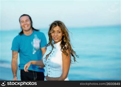 Portrait of a young woman standing on the beach with a mid adult man beside her
