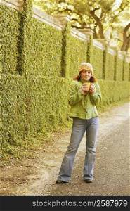 Portrait of a young woman standing on the roadside and holding a coffee cup