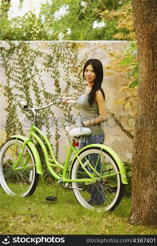 Portrait of a young woman standing with a bicycle