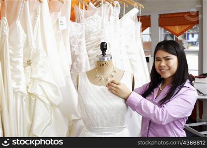 Portrait of a young woman standing with a mannequin in a clothing store