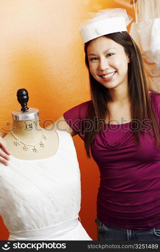 Portrait of a young woman standing with her arm around a mannequin