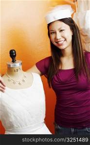 Portrait of a young woman standing with her arm around a mannequin