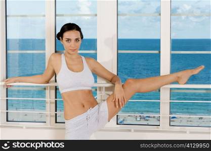 Portrait of a young woman stretching on the railing of a window