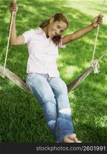 Portrait of a young woman swinging on a swing