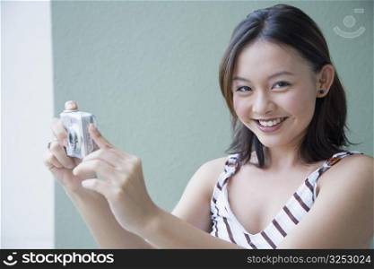 Portrait of a young woman taking a photograph from a digital camera