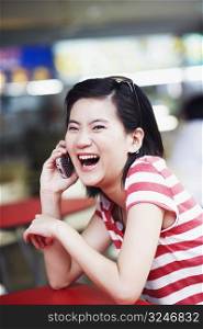 Portrait of a young woman talking on a mobile phone and laughing