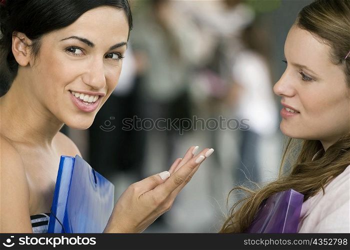 Portrait of a young woman talking to her friend and smiling