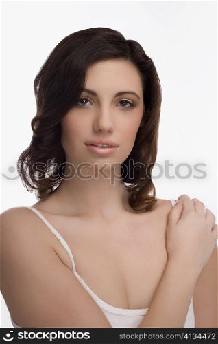 Portrait of a young woman touching her shoulder and smiling