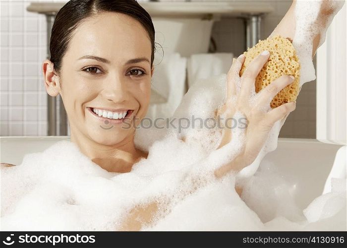 Portrait of a young woman using a bath sponge on her arm