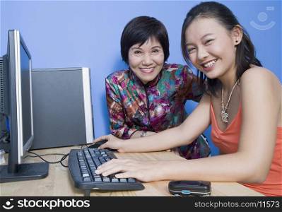 Portrait of a young woman using a computer with her mother sitting beside her