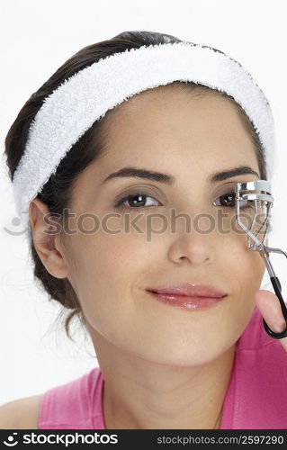 Portrait of a young woman using a eyelash curler