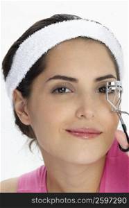 Portrait of a young woman using a eyelash curler