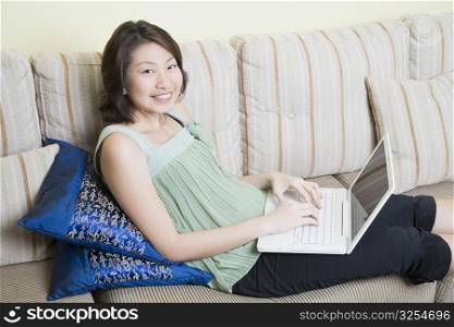 Portrait of a young woman using a laptop and smiling