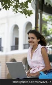 Portrait of a young woman using a laptop and smiling, Old San Juan, San Juan, Puerto Rico