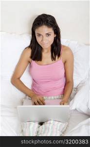 Portrait of a young woman using a laptop in bed