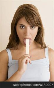 Portrait of a young woman using a tongue depressor