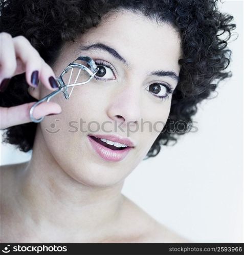 Portrait of a young woman using an eyelash curler