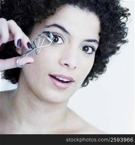 Portrait of a young woman using an eyelash curler