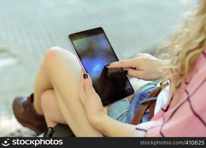 Portrait of a young woman using her tablet. Outdoors. Urban scene.