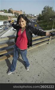 Portrait of a young woman walking on an overpass with her arms outstretched