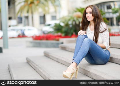 Portrait of a young woman, wearing casual clothes, with long hair in urban background