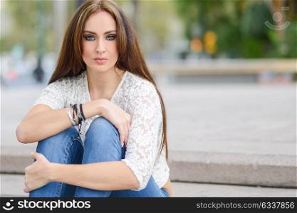 Portrait of a young woman, wearing casual clothes, with long hair in urban background