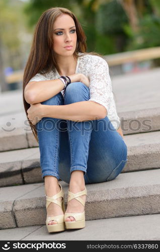 Portrait of a young woman, wearing casual clothes, with long hair in urban background