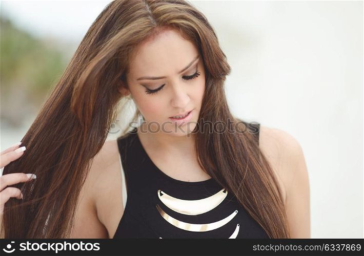 Portrait of a young woman, wearing dress, with long hair in urban background