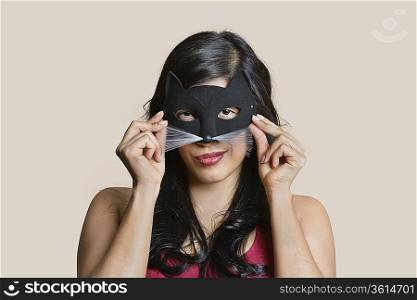 Portrait of a young woman wearing eye mask over colored background