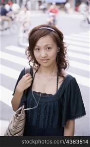 Portrait of a young woman wearing headphones and carrying a shoulder bag