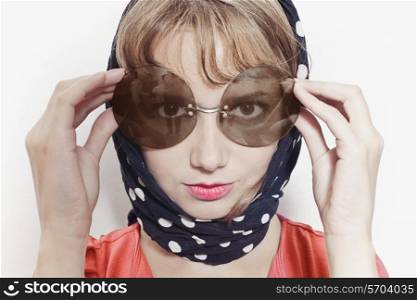 Portrait of a young woman wearing sunglasses and headscarf on a white background