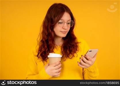 Portrait of a young woman while looking at a mobile phone while standing against isolated background.