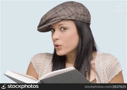 Portrait of a young woman whistling with a book in front of her