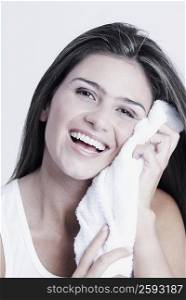 Portrait of a young woman wiping her face with a towel and smiling