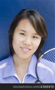 Portrait of a young woman with a badminton racket and smiling